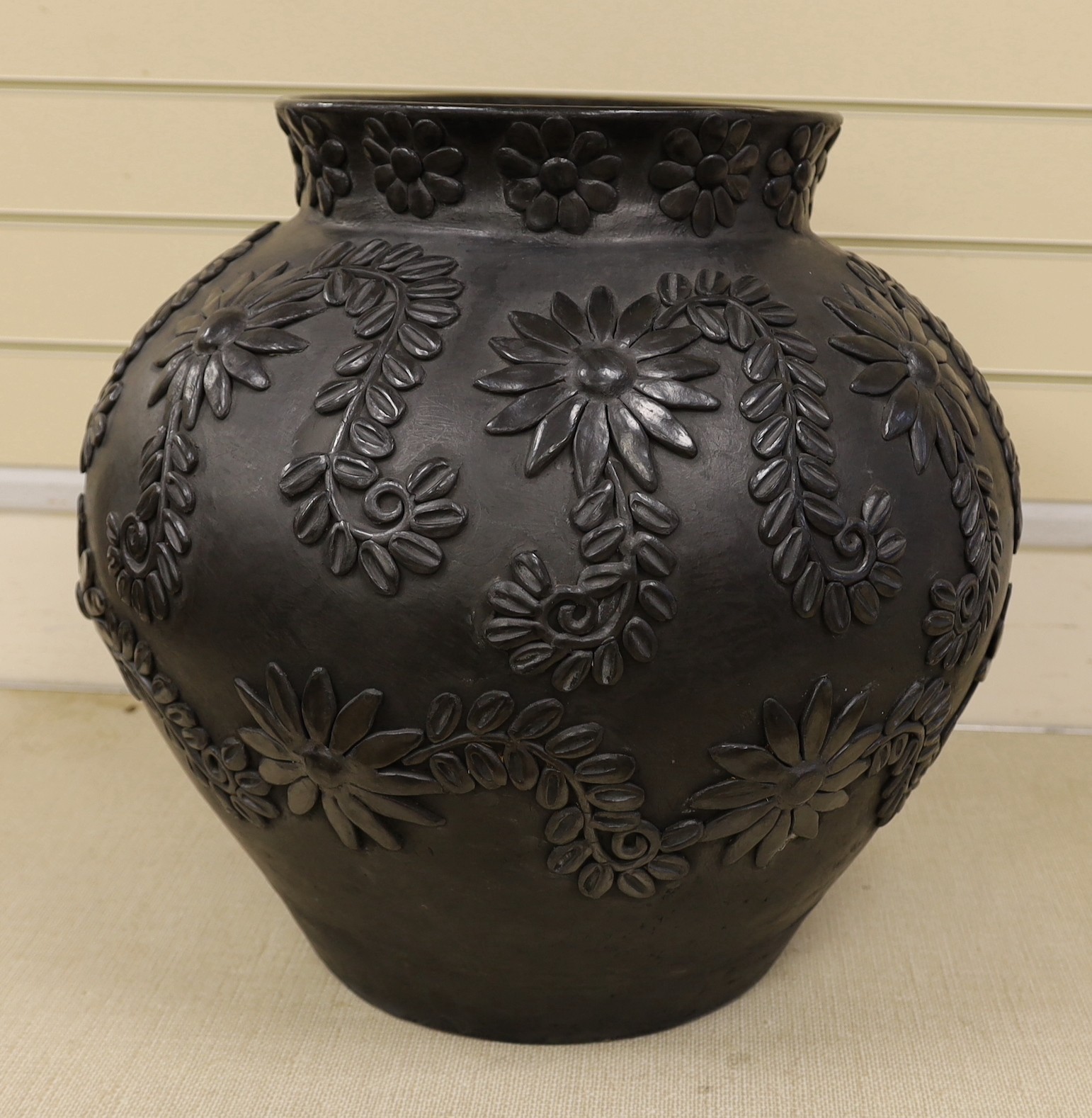 A large black-painted floral decorated terracotta vase, 50cm